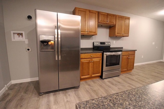 kitchen featuring dark countertops, light wood finished floors, baseboards, and appliances with stainless steel finishes
