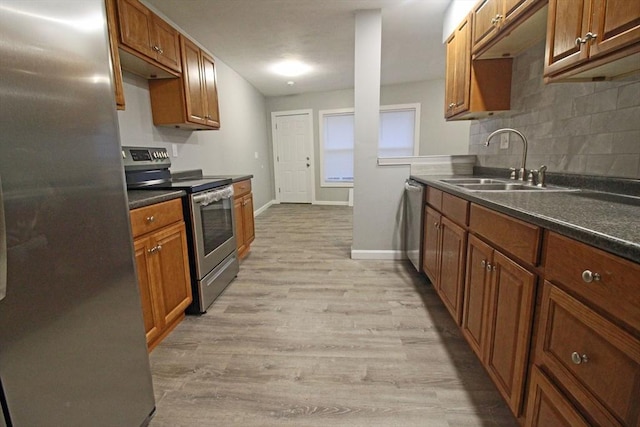 kitchen featuring tasteful backsplash, a sink, appliances with stainless steel finishes, light wood-style floors, and brown cabinets