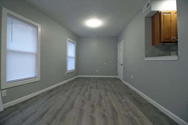 spare room featuring visible vents, baseboards, and dark wood finished floors