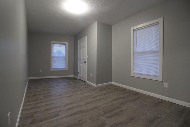 spare room with dark wood-style flooring, baseboards, and a textured ceiling