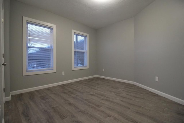 empty room featuring baseboards and dark wood-style floors