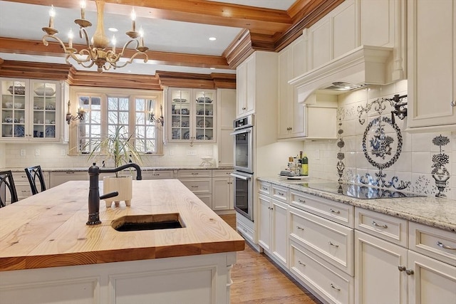 kitchen featuring beamed ceiling, glass insert cabinets, decorative backsplash, and a sink