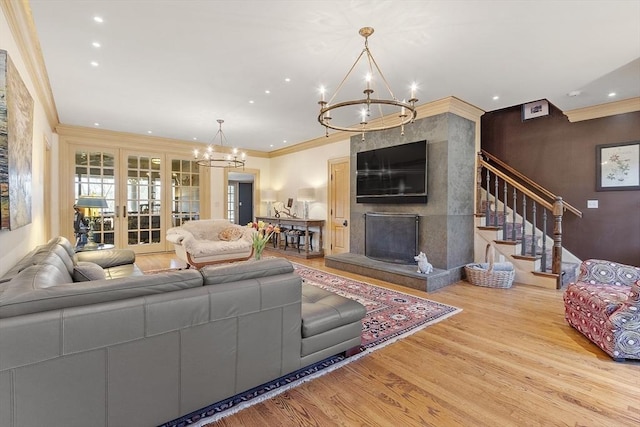 living room with wood finished floors, a premium fireplace, an inviting chandelier, recessed lighting, and crown molding