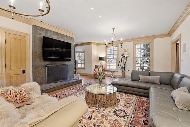 living area with crown molding, baseboards, a fireplace, wood finished floors, and a notable chandelier