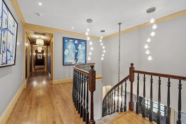 hall with visible vents, crown molding, attic access, an upstairs landing, and wood finished floors