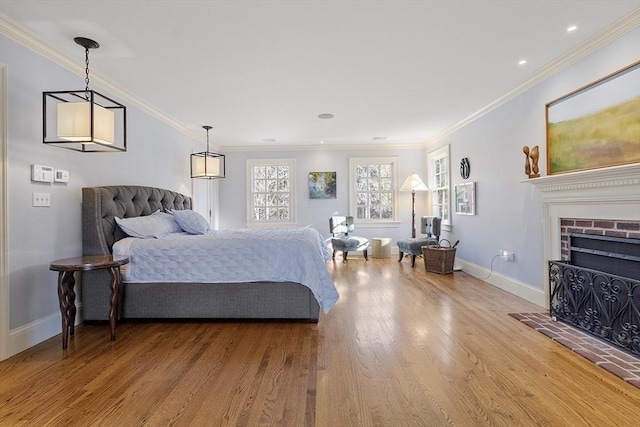 bedroom with crown molding, a brick fireplace, wood finished floors, and baseboards