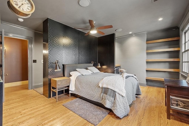 bedroom featuring baseboards, light wood-style flooring, an accent wall, and ornamental molding