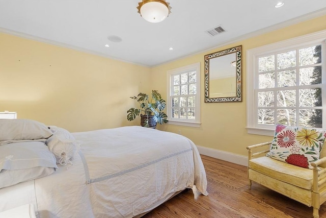 bedroom featuring visible vents, wood finished floors, and crown molding