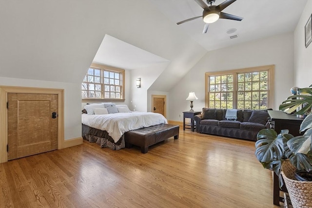 bedroom with a ceiling fan, wood finished floors, visible vents, baseboards, and vaulted ceiling