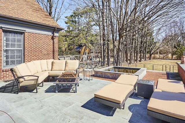 view of patio with an outdoor living space with a fire pit and fence