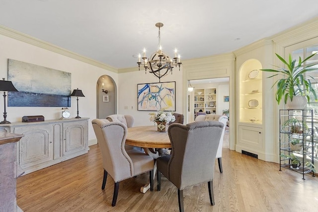 dining area featuring built in features, arched walkways, crown molding, and light wood finished floors