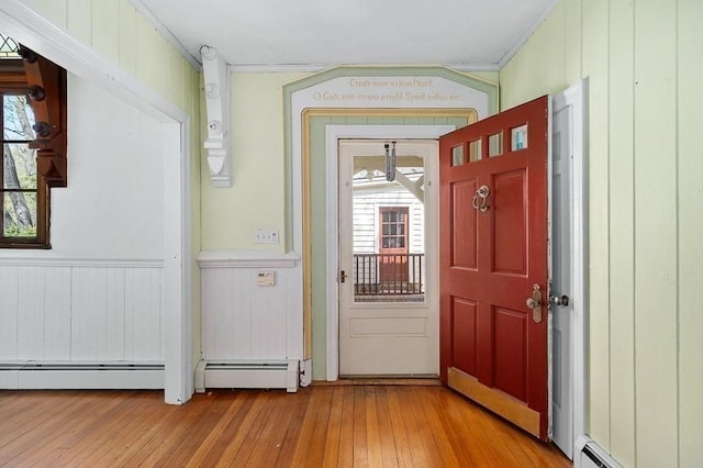 doorway with hardwood / wood-style flooring, a baseboard radiator, crown molding, a baseboard heating unit, and a wainscoted wall