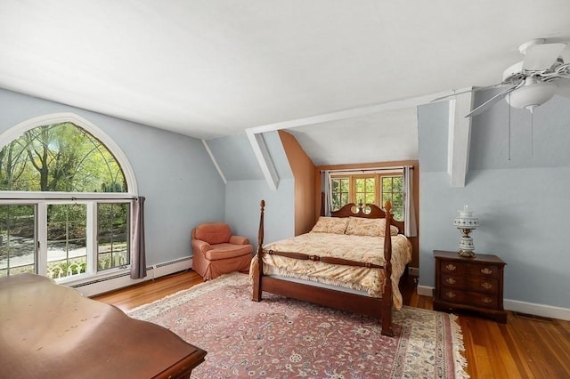 bedroom with a baseboard heating unit, lofted ceiling, wood finished floors, and baseboards