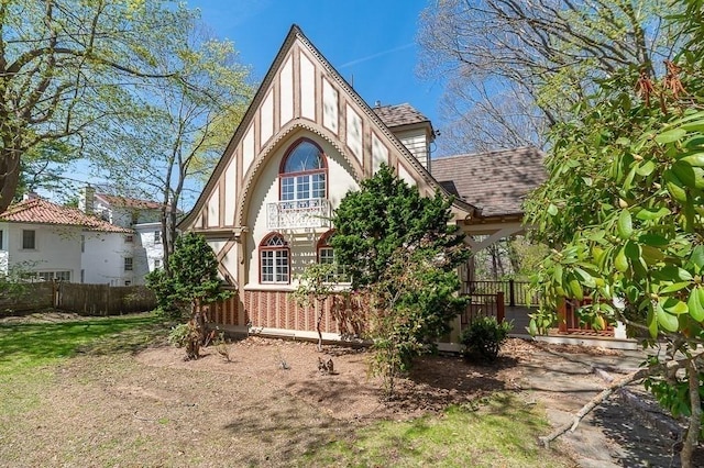 view of front facade with fence, roof with shingles, and stucco siding