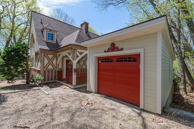 view of front of property featuring a chimney, driveway, roof with shingles, and an attached garage