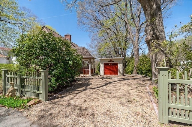 view of side of home with fence, dirt driveway, a chimney, and a garage