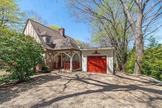 view of front of property with a porch, a garage, driveway, and a chimney