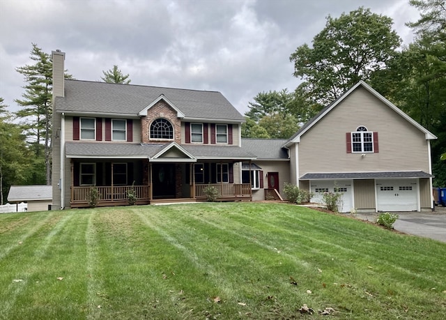 colonial home featuring covered porch, a front yard, and a garage