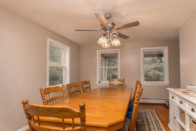 dining area with ceiling fan, light wood-type flooring, a baseboard heating unit, and a wealth of natural light