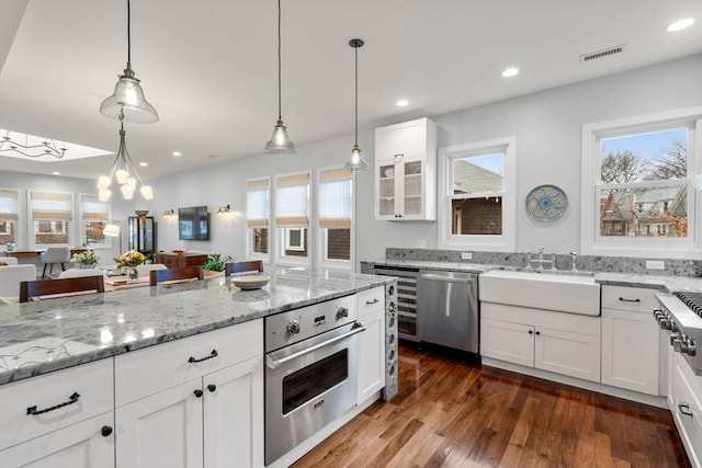 kitchen featuring visible vents, white cabinets, appliances with stainless steel finishes, hanging light fixtures, and a sink