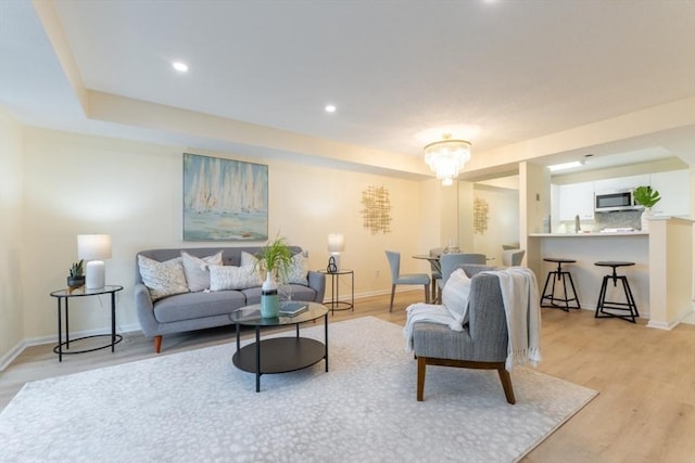 living room with an inviting chandelier and light hardwood / wood-style flooring