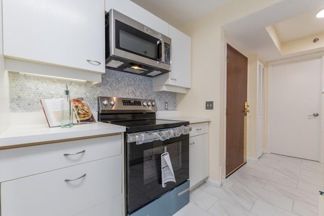 kitchen featuring backsplash, white cabinets, and appliances with stainless steel finishes