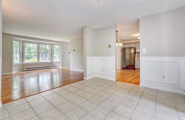 47 Key St Unit 47, Millis, MA 02054 - empty room with a baseboard radiator, light wood finished floors, wainscoting, and a decorative wall