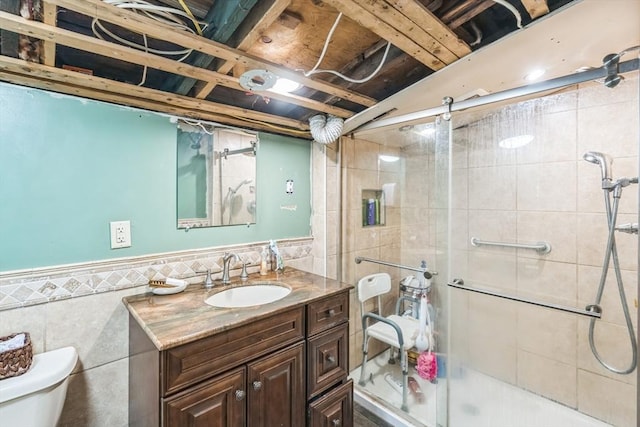 full bathroom with vanity, a shower stall, toilet, and tile walls