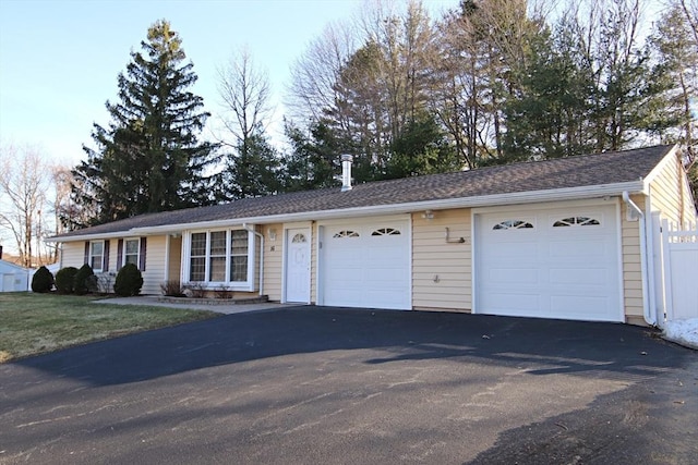 single story home with driveway, an attached garage, and fence