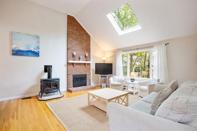 94 Pine View Dr, Brewster, MA 02631 - living area featuring a skylight, a wood stove, light wood-style flooring, high vaulted ceiling, and baseboard heating