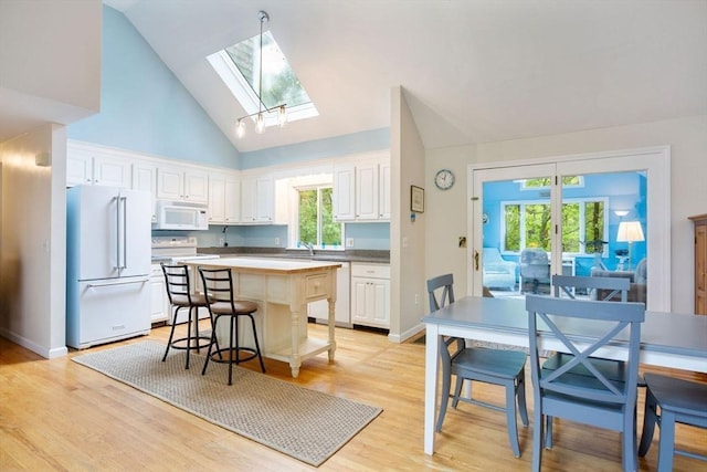 94 Pine View Dr, Brewster, MA 02631 - kitchen featuring white appliances, a skylight, white cabinetry, a center island, and light wood finished floors