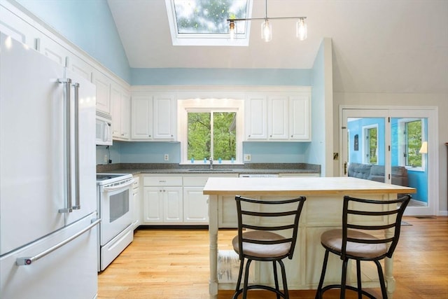 94 Pine View Dr, Brewster, MA 02631 - kitchen featuring white appliances, vaulted ceiling, white cabinets, and a kitchen breakfast bar