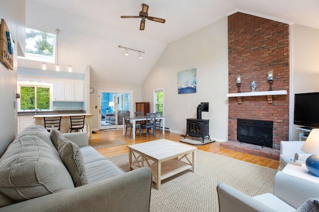 94 Pine View Dr, Brewster, MA 02631 - living area featuring a wood stove, light wood-style floors, plenty of natural light, ceiling fan, and high vaulted ceiling