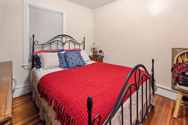 bedroom with crown molding, dark wood-type flooring, and a baseboard heating unit