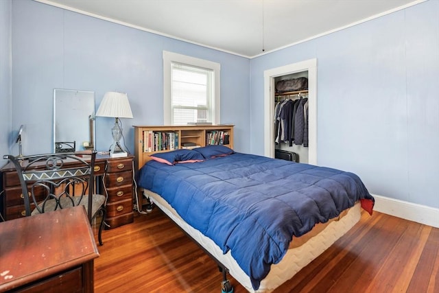 bedroom featuring hardwood / wood-style floors, ornamental molding, and a closet