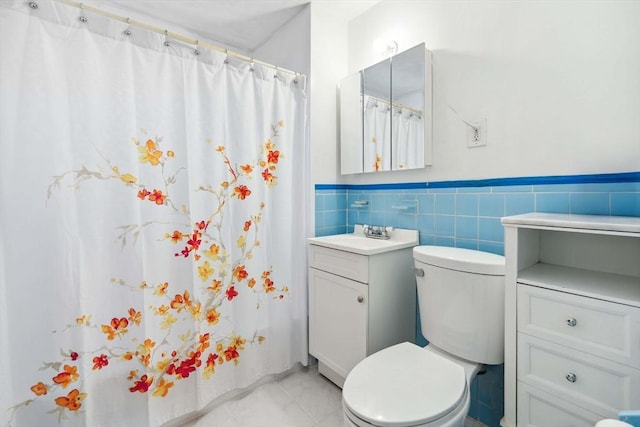 bathroom featuring vanity, toilet, and tile walls