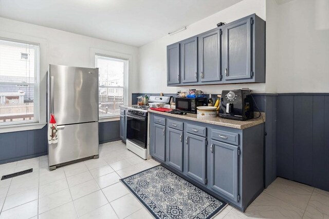 kitchen with stainless steel refrigerator, white gas range, and light tile patterned floors