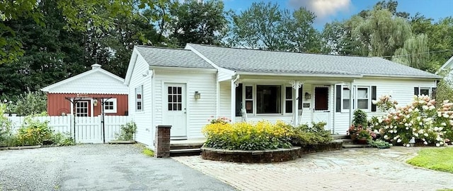 view of front of home featuring a shingled roof, a gate, fence, and a porch