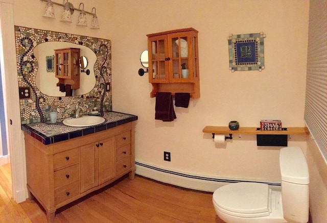 bathroom featuring vanity, wood finished floors, toilet, and decorative backsplash