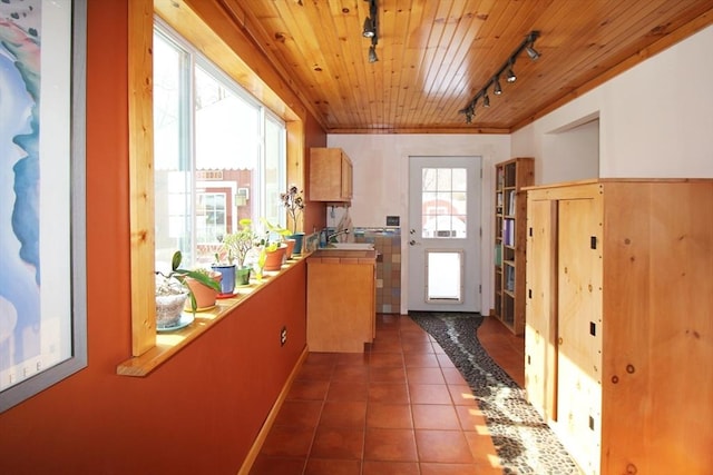 interior space with wood ceiling, dark tile patterned floors, and track lighting