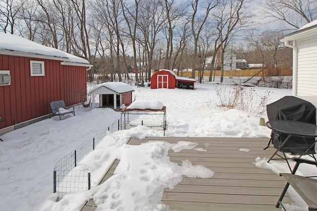 snow covered deck with a storage shed and an outdoor structure