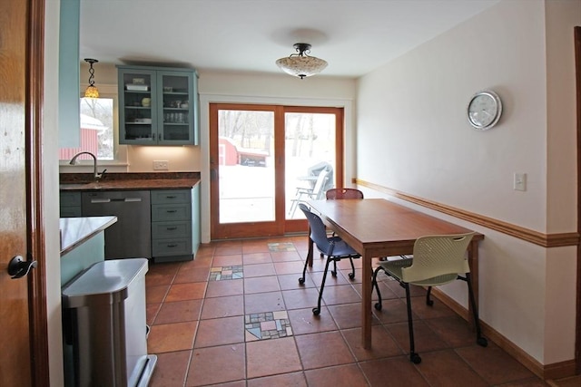 tiled dining area with a healthy amount of sunlight, baseboards, and a sink