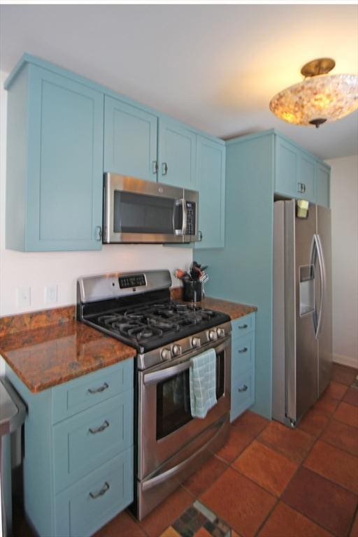 kitchen featuring blue cabinetry, stainless steel appliances, and dark stone countertops