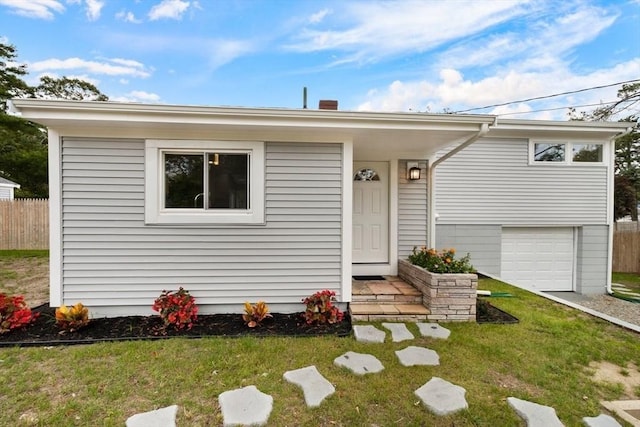 view of front of house featuring an attached garage, a front yard, and fence