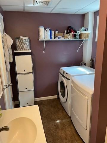 clothes washing area featuring laundry area, visible vents, a sink, baseboards, and washer and dryer