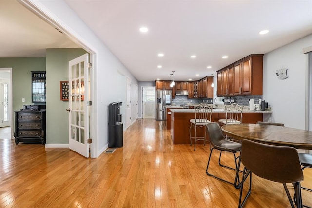 66 Eagle Dr, Dudley, MA 01571 - kitchen with stainless steel refrigerator with ice dispenser, a peninsula, under cabinet range hood, light wood-type flooring, and backsplash