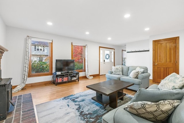 living room featuring light wood-type flooring, a wood stove, and a wealth of natural light