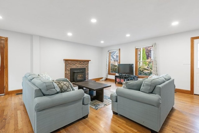 living room featuring a brick fireplace and light hardwood / wood-style flooring