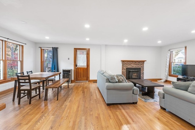 living room with light hardwood / wood-style floors and a brick fireplace