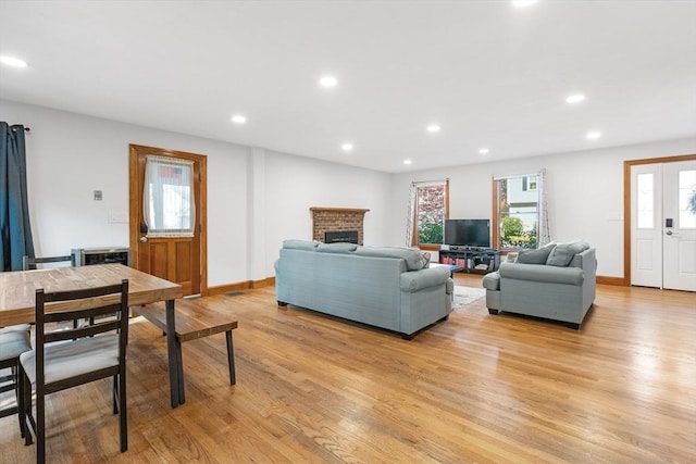 living room featuring light hardwood / wood-style floors and a brick fireplace